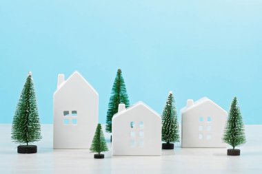 Sevimli küçük beyaz evler ve Noel dekorasyonu metnin üzerinde kopya alanı ile pastel arka plan mavi. Noel kutlamaları fikir