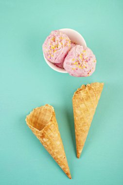Akuamarin arka plan üzerinde tepesi ile beyaz kase çilek li dondurma kepçeler, üst görünümü