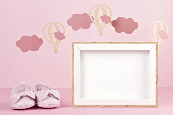 Baby girl cute pink shoes over the pink pastel background with clouds and ballons. Baby shower, girl birthday concept