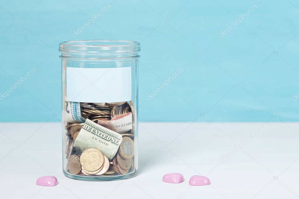 Coins and banknotes in glass money jar, financial donations, cha