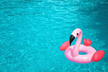 Yüzme havuzunun mavi suyunda şişme pembe flamingo. Toplam