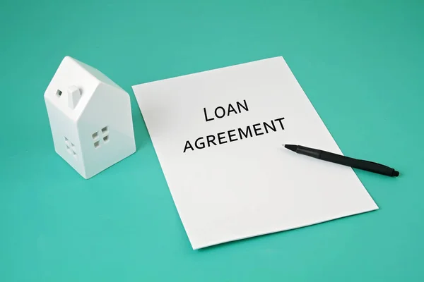 Loan agreement waiting for signature, house and pen on aquamarin