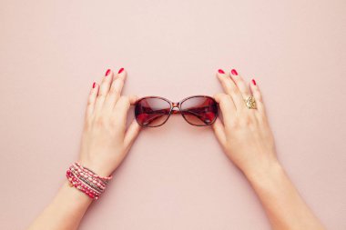 Pembe pastel arka plan üzerinde trendy güneş gözlüğü üst görünümü iki kadın elleri tarafından tutun