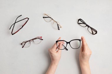 Gözlük tutan kadın. Optik mağaza, gözlük seçimi, göz testi, göz doktorunda vizyon muayenesi moda aksesuarları konsepti. Üst manzara, düz uzanma