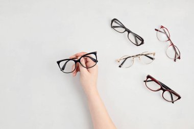 Gözlük tutan kadın. Optik mağaza, gözlük seçimi, göz testi, göz doktorunda vizyon muayenesi moda aksesuarları konsepti. Üst manzara, düz uzanma