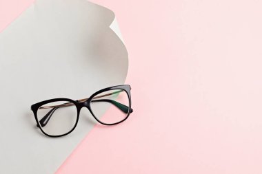 Pastel arka plan üzerinde şık gözlükler. Optik mağaza, gözlük seçimi, göz testi, göz doktorunda vizyon muayenesi moda aksesuarları konsepti. Üst manzara, düz uzanma