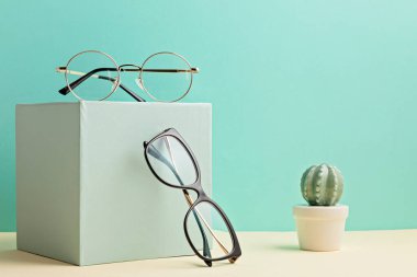 Pastel arka plan üzerinde şık gözlükler. Optik mağaza, gözlük seçimi, göz testi, göz doktorunda vizyon muayenesi moda aksesuarları konsepti. Ön görünüm 