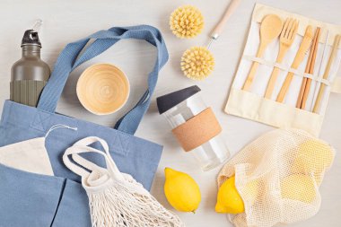 Sıfır atık. Çevre dostu bambu çatal bıçak takımı, ağ pamuk torbası, yeniden kullanılabilir kahve bardağı, fırçalar ve su şişesi. Sürdürülebilir, etik, plastik içermeyen konsept