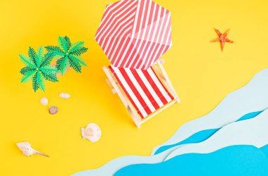 Güneş yatağı, oyuncak palmiye ağaçları, kağıt deniz dalgaları. Yaz tatilleri, sahil tatilleri, tatil konsepti.