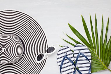 Yaz tatili, seyahat, turizm konsepti. Tropik plaj aksesuarları şapka ve parmak arası terliklerle üstten görünüyor.