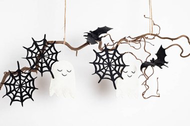 Beyaz duvarda asgari cadılar bayramı süsü asılı. Tebrik kartı, tatil dekorasyonu konsepti. Boşluğu kopyala