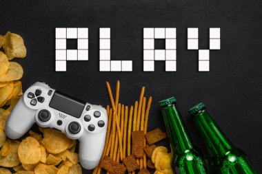 Modern beyaz gamepad cips, kraker ve siyah bir zemin üzerine bira şişesi arasında. Oyun kavramını.