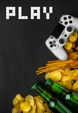 Modern beyaz gamepad cips, kraker ve siyah bir zemin üzerine bira şişesi arasında. Oyun kavramını.