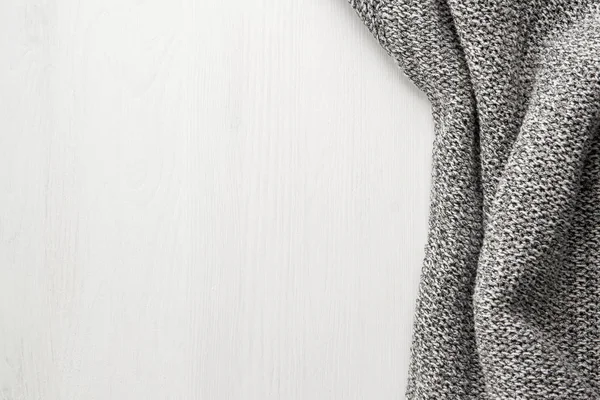 Gray knitted cloth on a white wooden background. oncept of rustic white background.