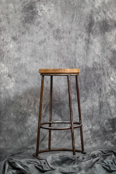 metal bar stool with a wooden seat on a gray fabric background