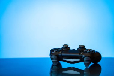 modern siyah gamepad parlak bir yüzey ve bir parlayan mavi arka plan