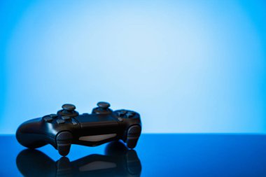 modern siyah gamepad parlak bir yüzey ve bir parlayan mavi arka plan