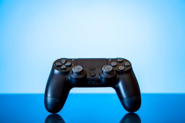 modern siyah gamepad parlak bir yüzey ve bir parlayan mavi arka plan