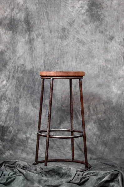 metal bar stool with a wooden seat on a gray fabric background