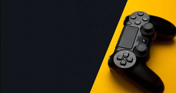 黒と黄色の背景にモダンな黒い無線ゲームパッド — ストック写真