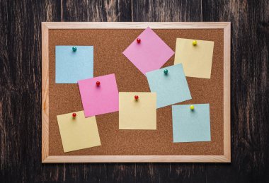 corkboard koyu ahşap zemin üzerine sabitlenmiş çok renkli çıkartmaları ile. Çok renkli boş posta o notlar bir mantar hakları Kurulu.