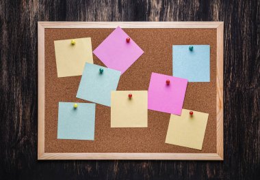 corkboard koyu ahşap zemin üzerine sabitlenmiş çok renkli çıkartmaları ile. Çok renkli boş posta o notlar bir mantar hakları Kurulu.