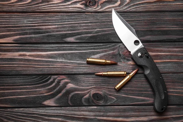 knife and cartridges on a dark wooden background