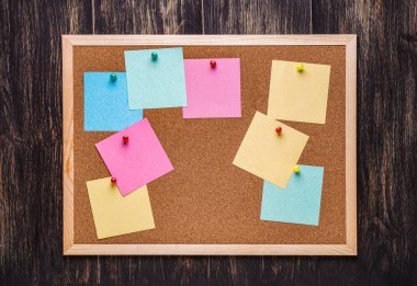 corkboard koyu ahşap zemin üzerine sabitlenmiş çok renkli çıkartmaları ile. Çok renkli boş posta o notlar bir mantar hakları Kurulu.