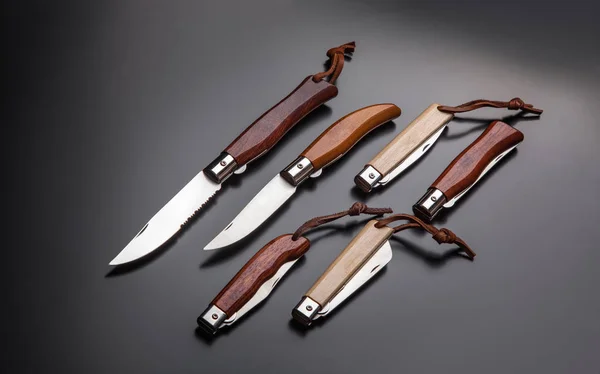Складные перьевые ножи с деревянными ручками на градиенте серо-черного цвета — стоковое фото