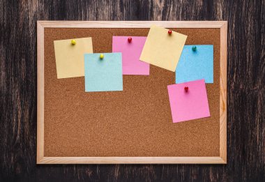 corkboard koyu ahşap zemin üzerine sabitlenmiş çok renkli çıkartmaları ile. Çok renkli boş posta o notlar bir mantar hakları Kurulu.
