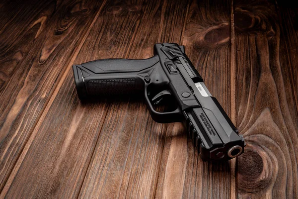 Pistola preta em uma mesa de madeira marrom — Fotografia de Stock