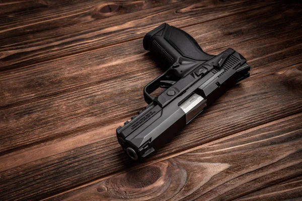 Pistola preta em uma mesa de madeira marrom — Fotografia de Stock