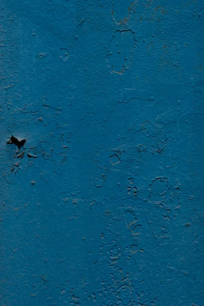 The blue metal surface is cracked by time. Peeling paint rusting