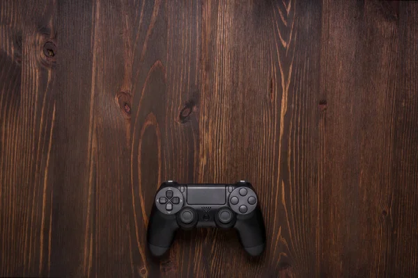 Gamepad negro moderno sobre un fondo de madera oscura. Concepto de juego w — Foto de Stock