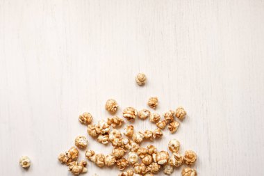 Beyaz ahşap bir arka plan üzerinde karamelize patlamış mısır. Karamel popcor