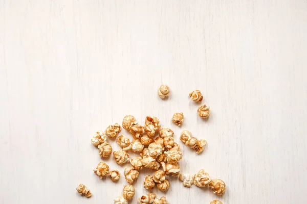 Caramelized popcorn on a white wooden background. Caramel popcor