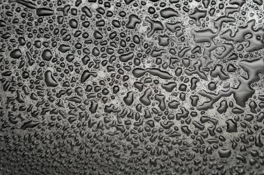 Koyu bir bardağa parlak su damlaları. Siyah yüzeyde su damlaları.