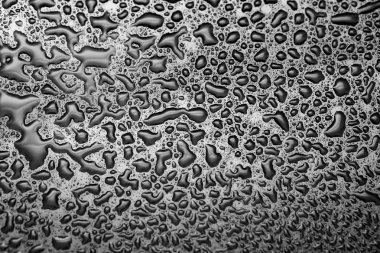 Koyu bir bardağa parlak su damlaları. Siyah yüzeyde su damlaları.