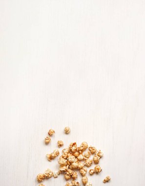 Beyaz ahşap bir arka plan üzerinde karamelize patlamış mısır. Karamel popcor