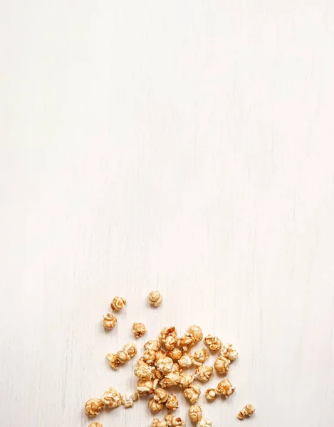 Карамелізований попкорн на білому дерев'яному тлі. карамельний попкорн — стокове фото