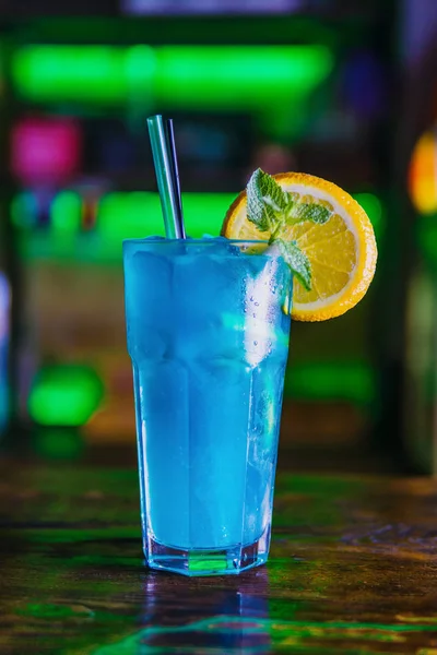 Blue cocktail in a high glass glass with a slice of orange. Colo