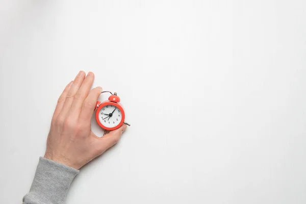 La mano de un joven sostiene un despertador rojo. Tiempo, sueño, aw —  Fotos de Stock