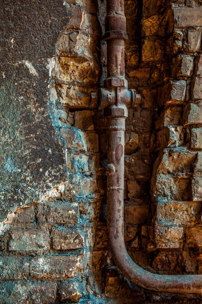 Old rusty water pipe in a brick wall.  Old rusty pipe with valve
