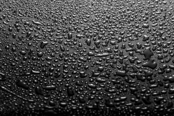 Glänsande vatten droppar på ett mörkt glas. Vattendroppar på svart yta. — Stockfoto