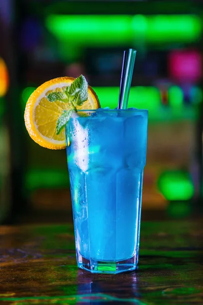 Blue cocktail in a high glass glass with a slice of orange. Colo