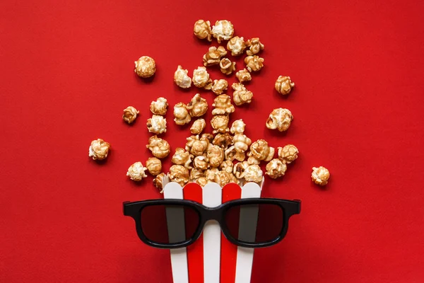 Popcorn in a red and white cardboard box with glasses for a 3D m