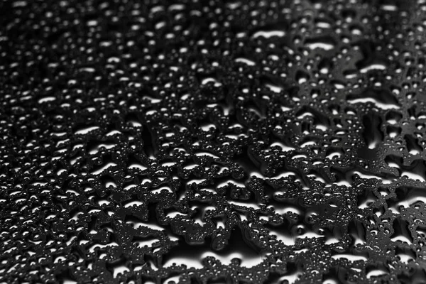 Glänsande vatten droppar på ett mörkt glas. Vattendroppar på svart yta. — Stockfoto
