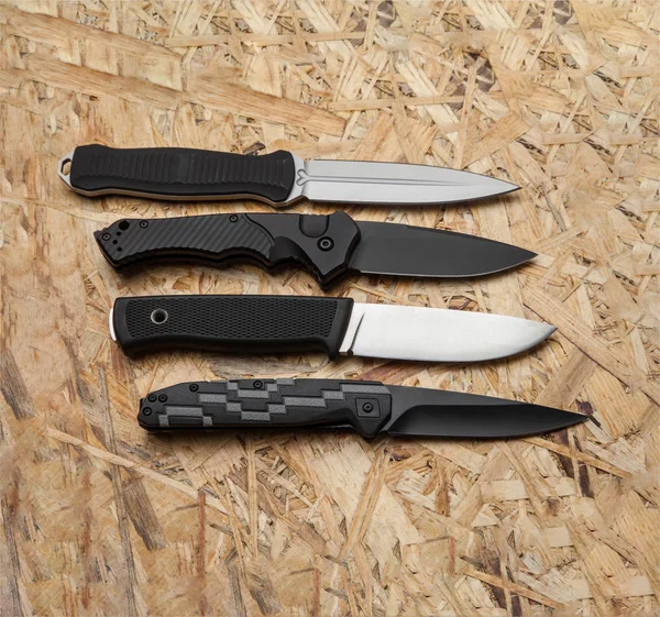 Diversi coltelli da caccia e pennini su uno sfondo di legno chiaro — Foto Stock