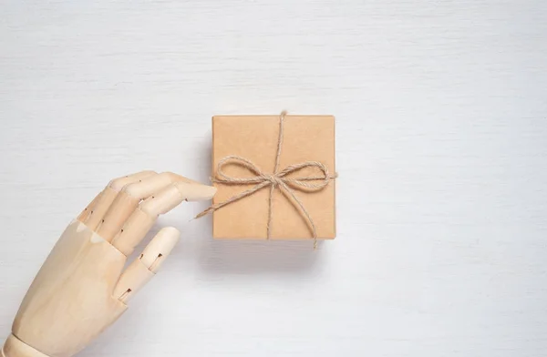 Wooden mannequin hand opens a gift in a box tied with twine. Gif