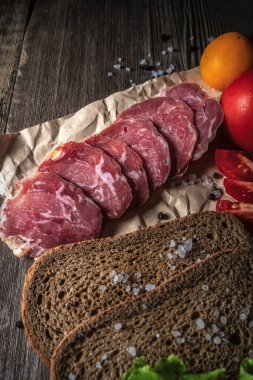 Tahtada dilimlenmiş kurutulmuş et. Sebzeler, ekmek ve et masada. Bir sandviçin bileşenleri.